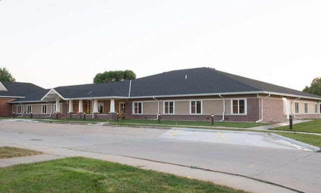 Outside View of a Modern, Single Story, Red Brick Senior Living Home with a Grand Entryway Complete with Angled, White Columns