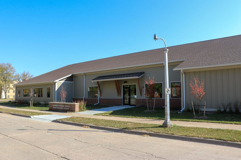 Single story, tan building connected to adjacent street by newer looking concrete sidewalk