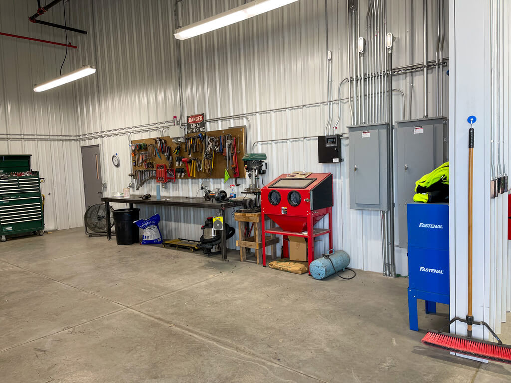 A corrugated, white metal wall with a workbench, and several tools